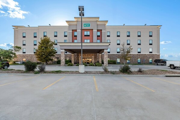 A hotel with a central entrance, multiple floors, and a parking lot.