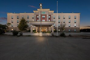 A modern hotel with a central entrance, multiple floors, and a sign indicating 'Quality'.