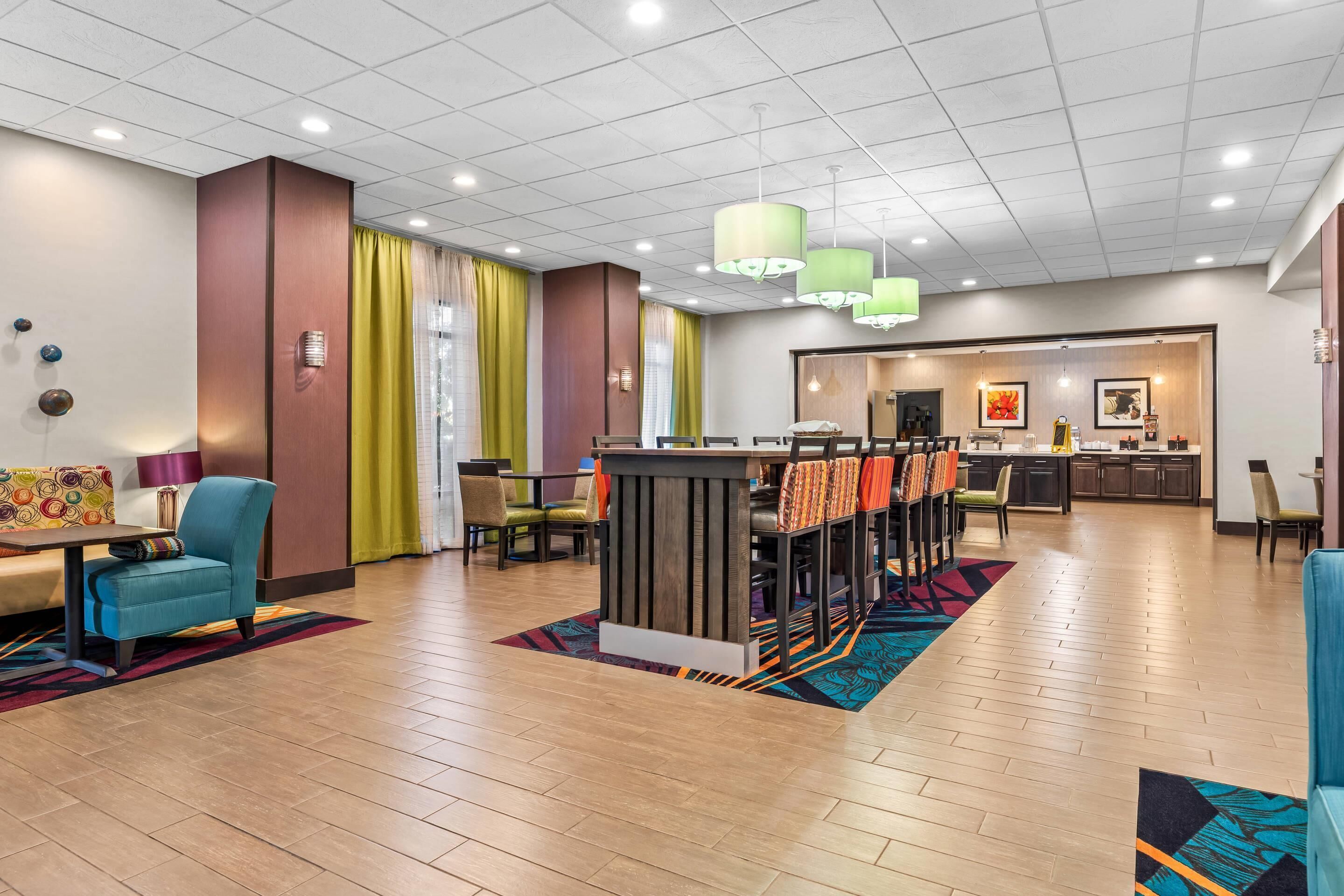 Un hall de hotel con mostrador de recepción, zona de estar y vistas hacia la cocina.