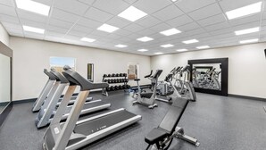Ein Fitnessstudio mit Laufbändern, Hanteln und Kraftgeräten.