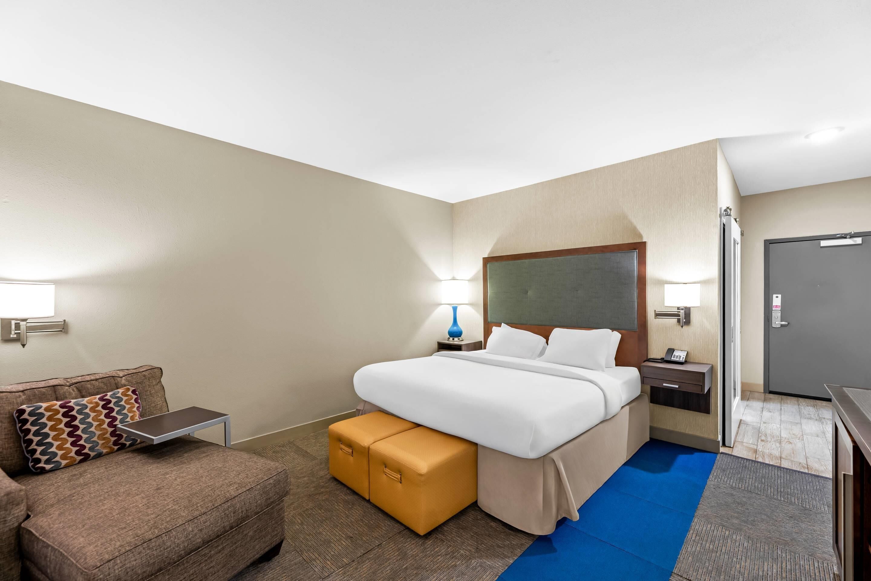 Une chambre d’hôtel avec un lit, un bureau, une chaise et un petit canapé.