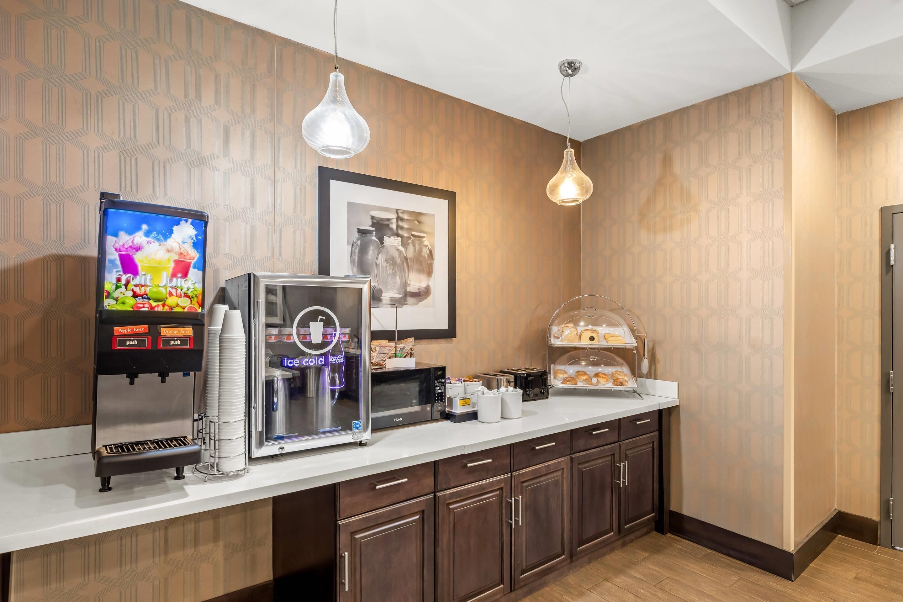 A hotel room with a kitchenette, including a coffee machine, a microwave, and a food display.
