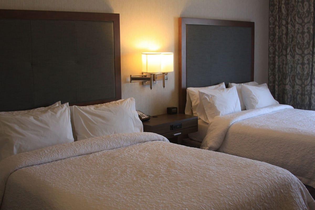 Una habitación de hotel con dos camas, una mesita de noche, una lámpara y un teléfono.