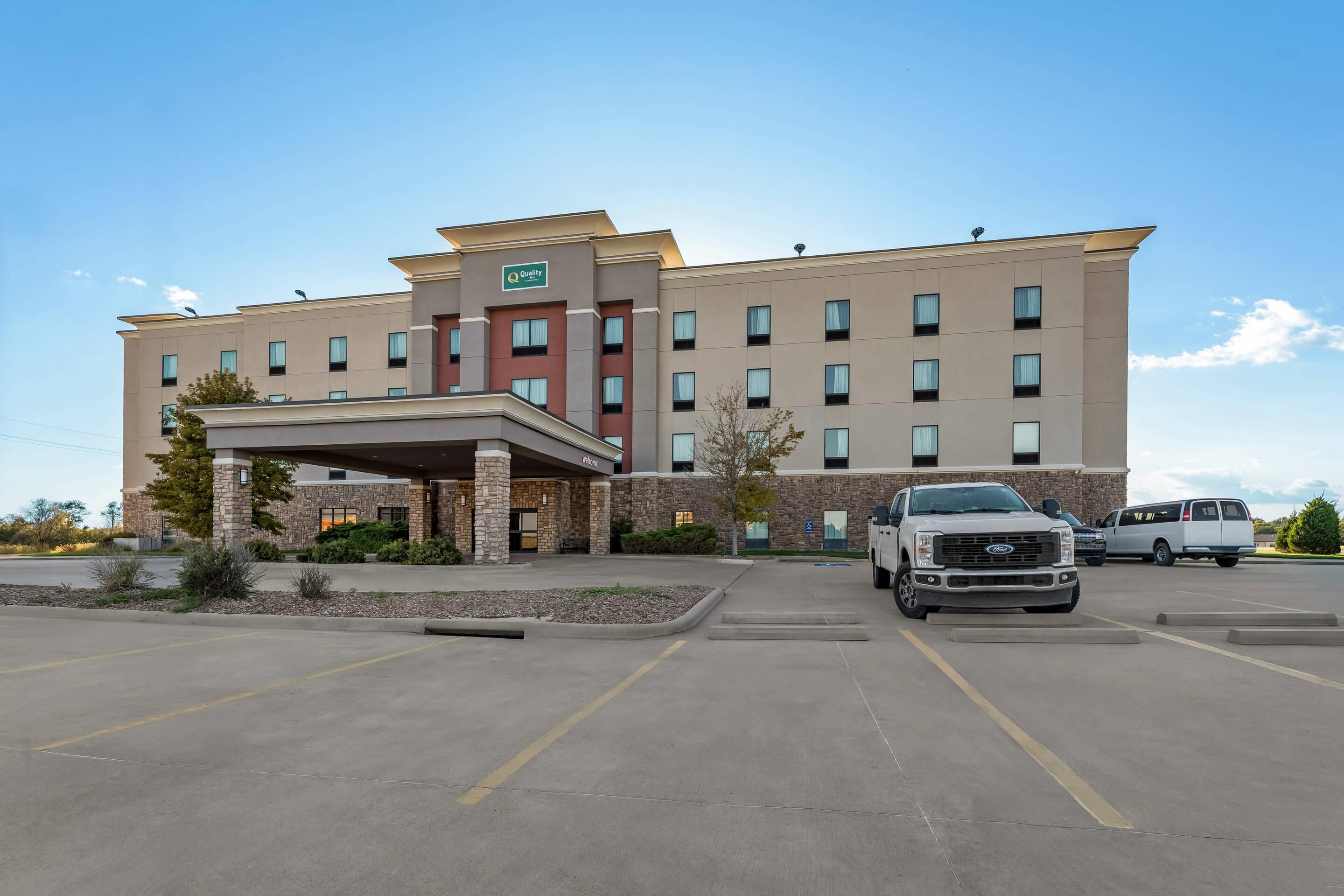 Um hotel com design moderno, apresentando uma entrada coberta e vários espaços de estacionamento.