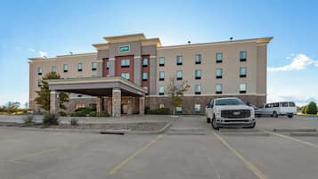 Um hotel com design moderno, apresentando uma entrada coberta e vários espaços de estacionamento.