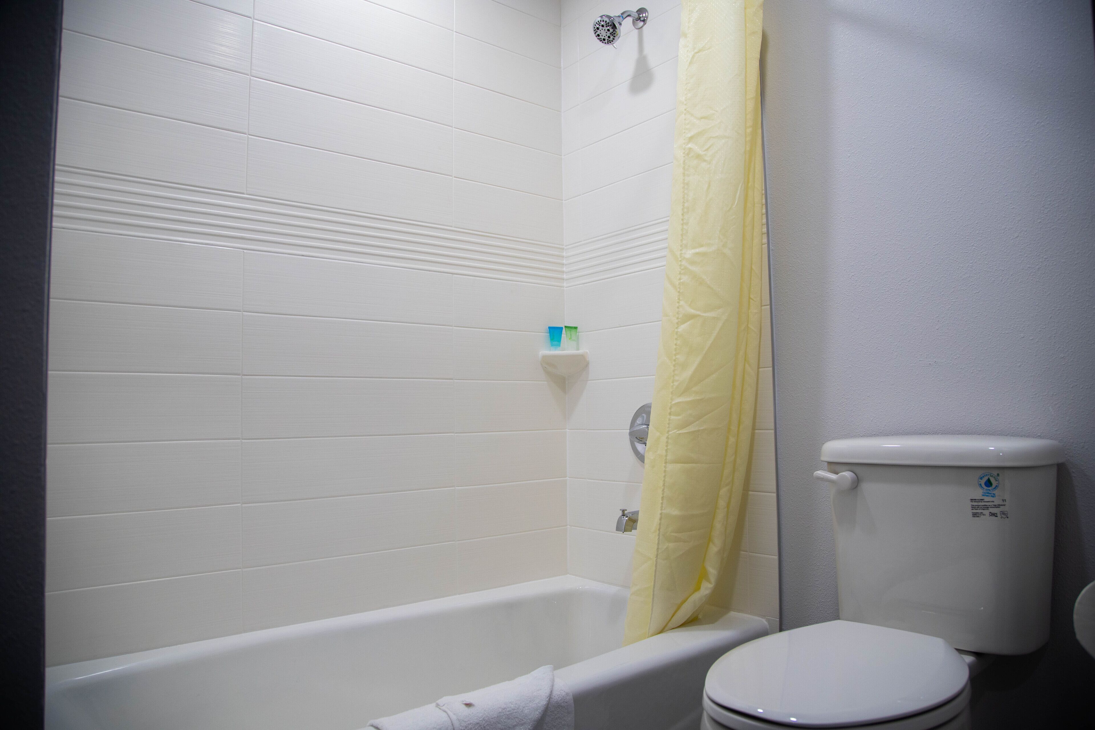 A bathroom with a bathtub, toilet, and a yellow shower curtain.