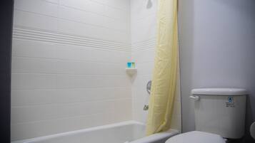 A bathroom with a bathtub, toilet, and a yellow shower curtain.