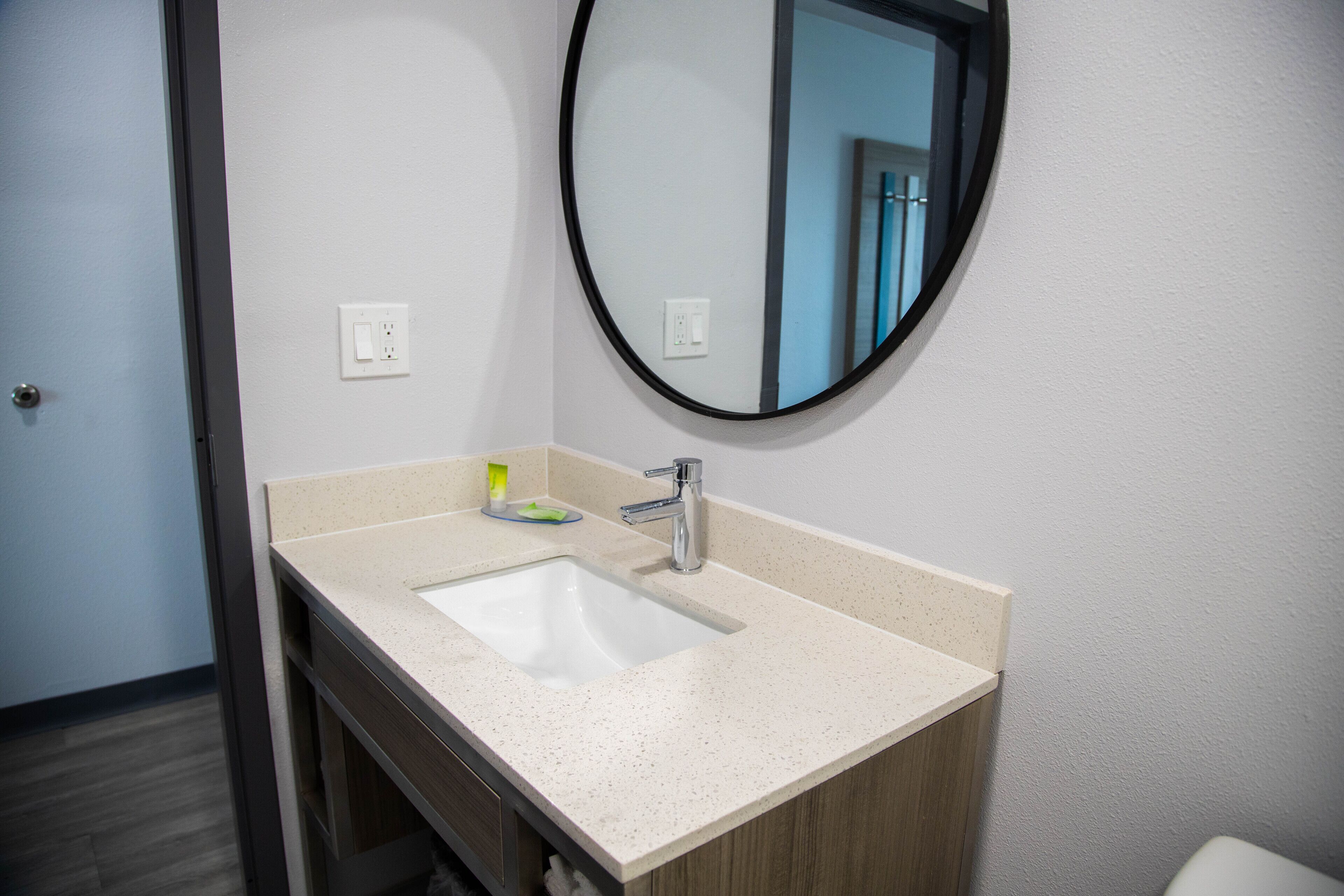 A bathroom with a white sink, a mirror, and a wooden cabinet.