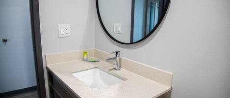 A bathroom with a white sink, a mirror, and a wooden cabinet.