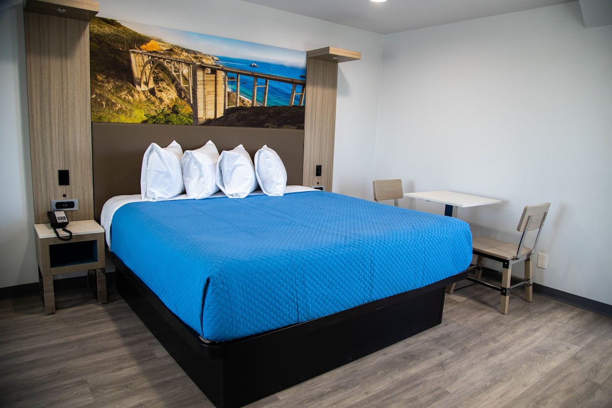 A hotel room with a large bed, a desk, and a chair.
