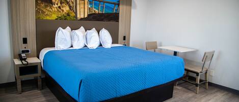 A hotel room with a large bed, a desk, and a chair.