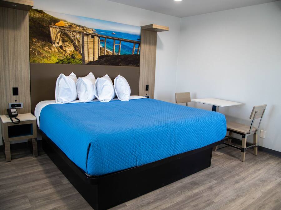 A hotel room with a large bed, a desk, and a chair.