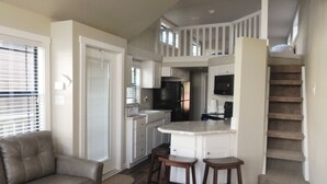 A compact living space with a kitchenette, a sofa, and a staircase. - Pope's Landing Marina (Alba)