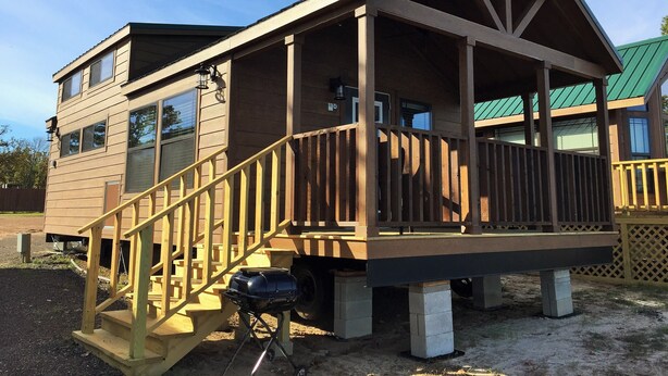 A two-story wooden cabin with a balcony and a barbecue grill outside. - Pope's Landing Marina (Alba)