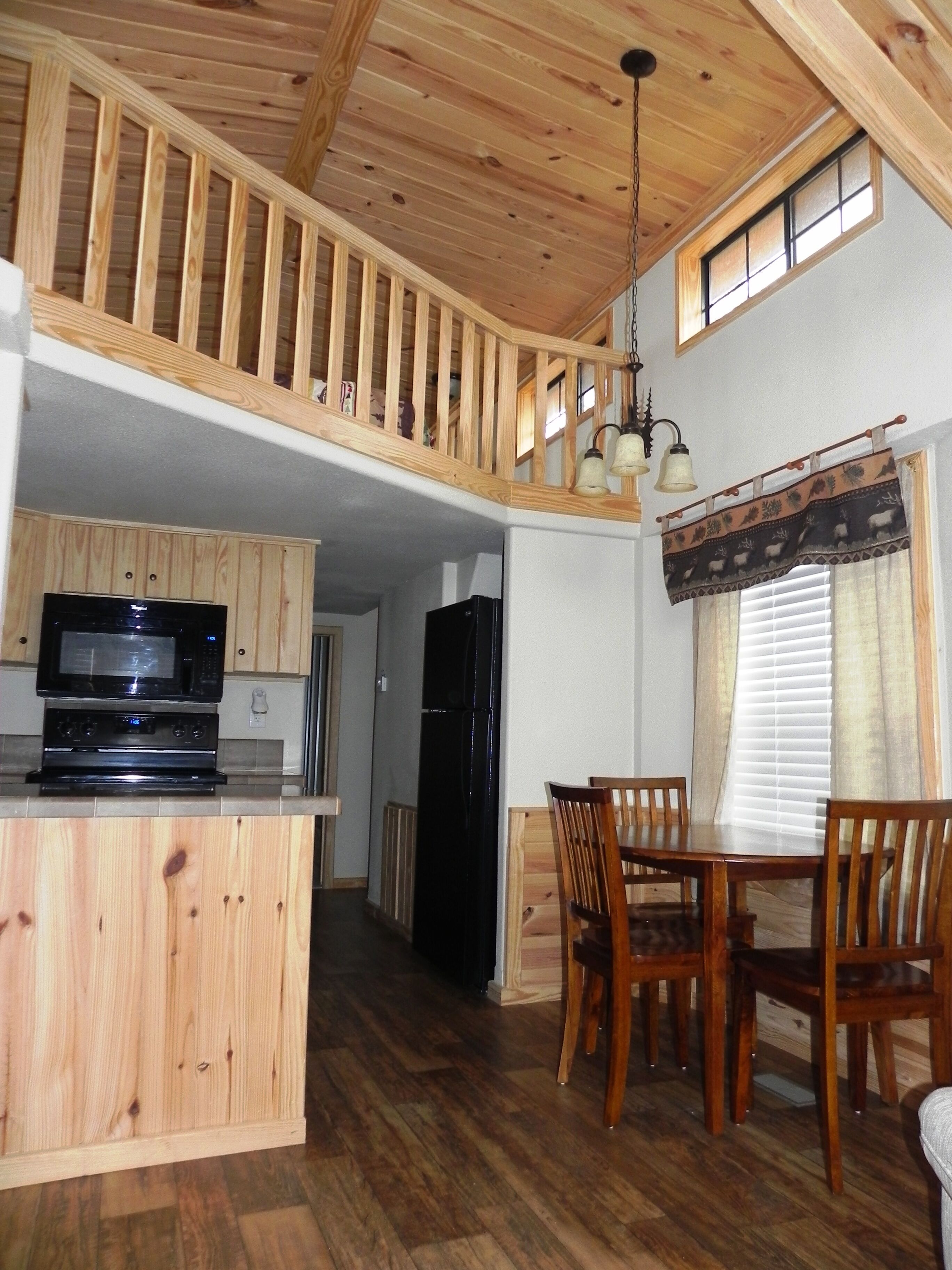 A spacious kitchen with wooden cabinets, a black refrigerator, and a dining area with wooden chairs and a table.