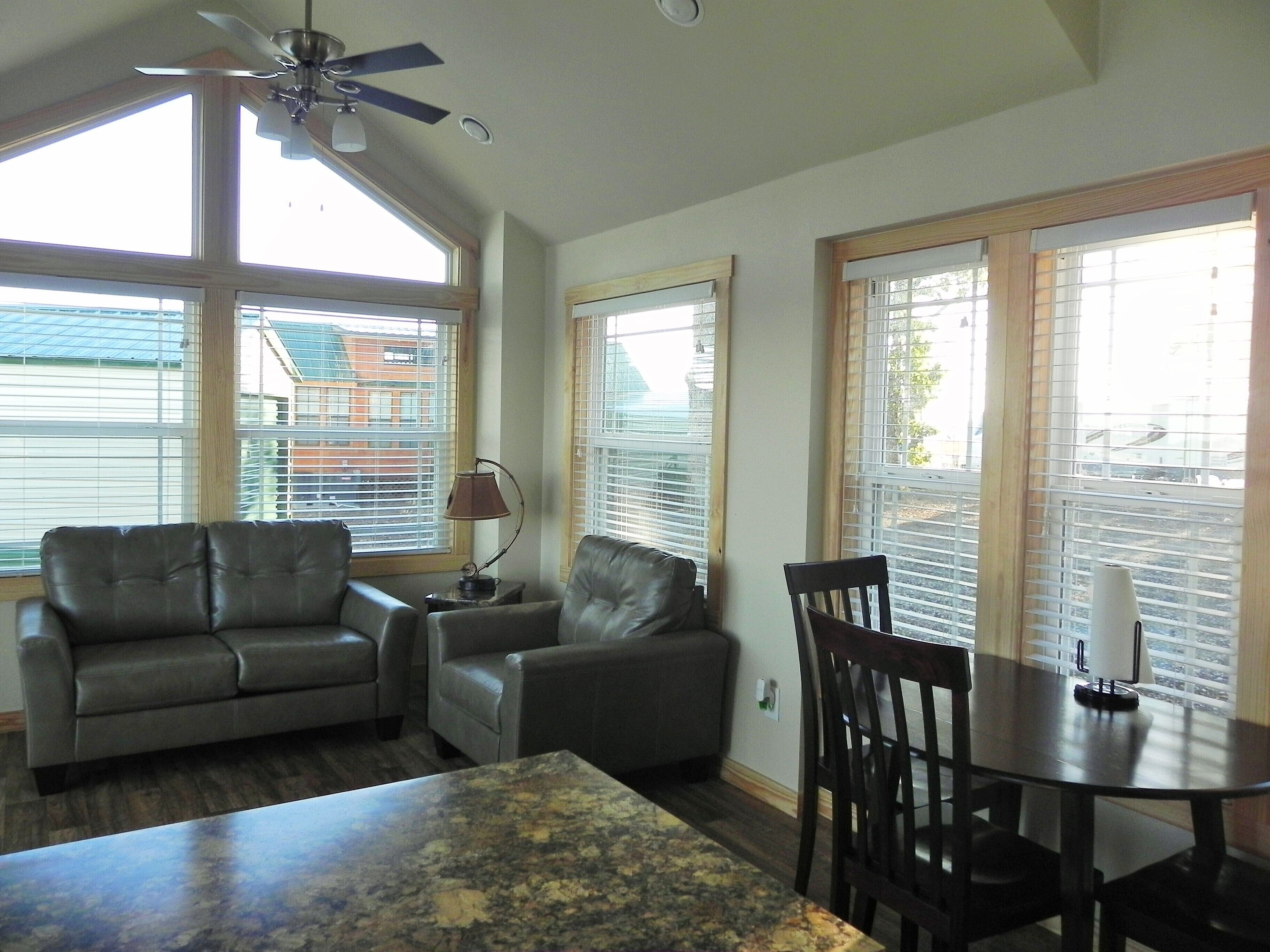 A living room with a ceiling fan, two leather sofas, a coffee table, and a dining table with chairs.