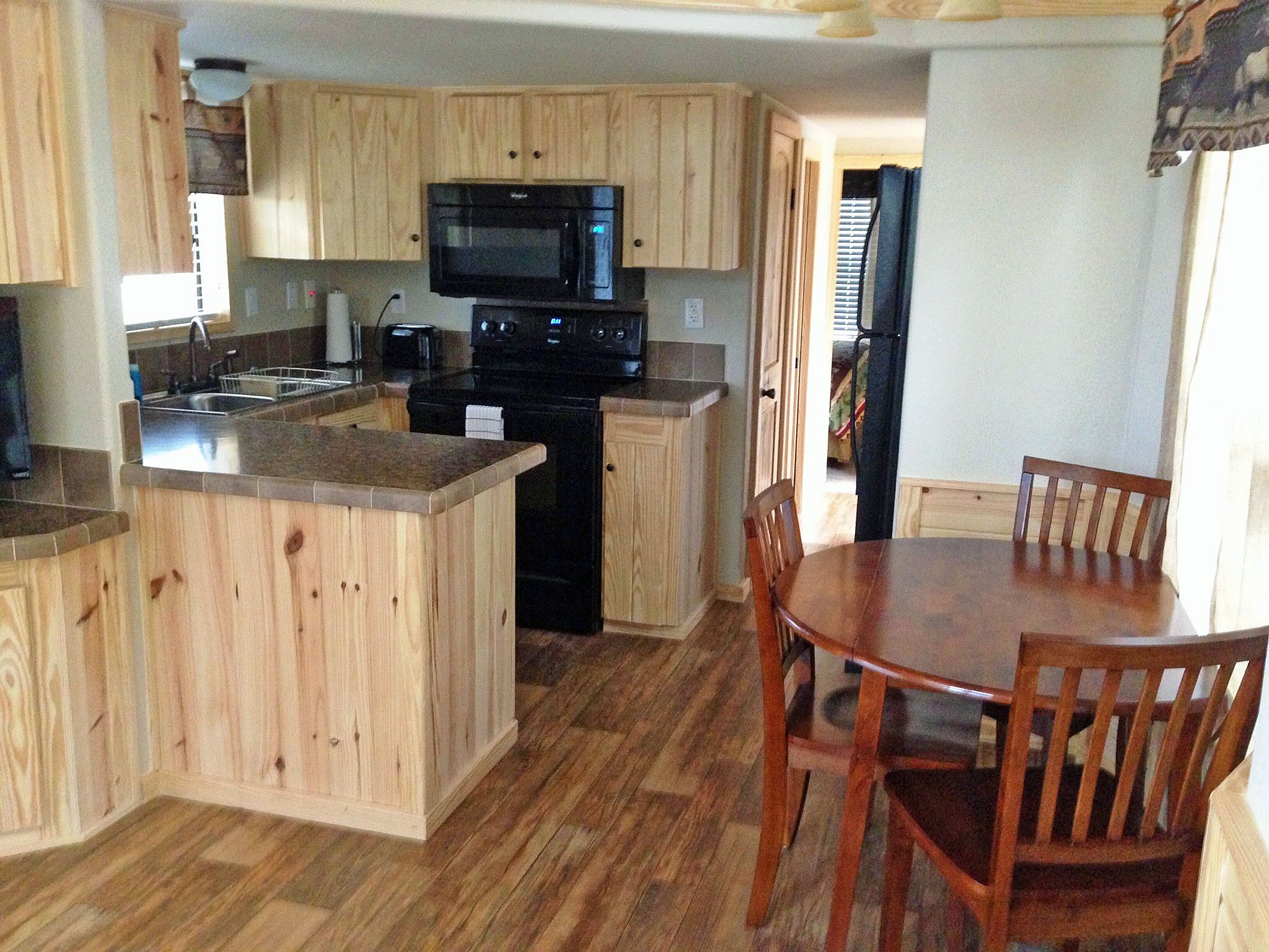 Una cocina con armarios de madera, un microondas, una estufa y un comedor con una mesa y sillas.