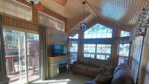 A cozy living room with a fireplace, a television, and a large window. - Pope's Landing Marina (Alba)