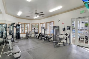 Ein Fitnessstudio mit unterschiedlichen Trainingsgeräten, großen Fenstern und einem Notausgang.