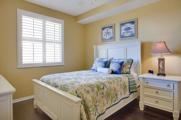 A bedroom with a bed, bedside tables, a lamp, and artwork on the wall.