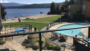 A pool area with a view of a lake, a beach, and a mountain range.