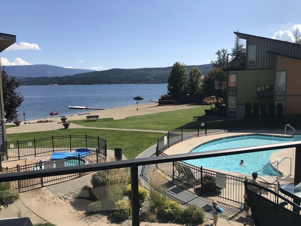 Zona de piscina con vistas a un lago, una playa y una cordillera.
