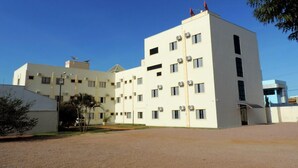 A multi-story building with a flat roof, several air conditioning units, and a clear sky. - Hotel Pequeno Mundo II (Campo Verde)