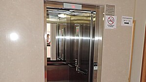 An elevator with a red carpet leading to it, a no-smoking sign, and a sign indicating the direction to the apartment. - Hotel Pequeno Mundo II (Campo Verde)
