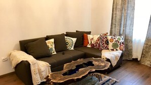 Ein Wohnzimmer mit einem dunkelgrauen Sofa, verziert mit gemusterten Kissen, einem rustikalen Holztisch und einem Teppich mit Muster.