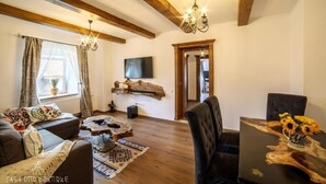 Ein gemütliches Wohnzimmer mit einer Couch, einem Couchtisch und einem an der Wand befestigten Fernseher.