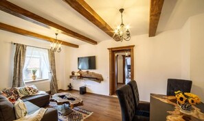 A cozy living room with a sofa, a coffee table, and a TV mounted on the wall. - Deluxe Apartment with A/C, Under the Clock Tower (Sighișoara)