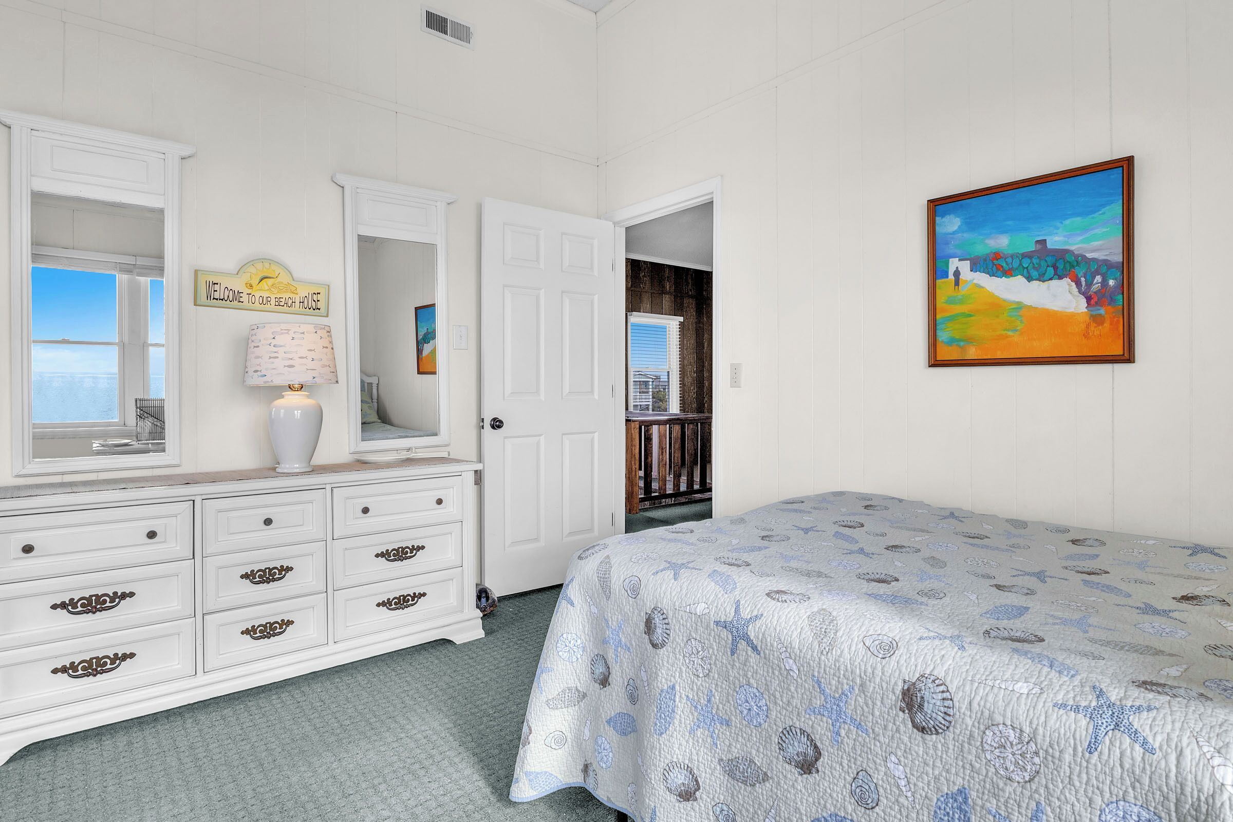 A bedroom with a bed, dresser, and a painting on the wall.