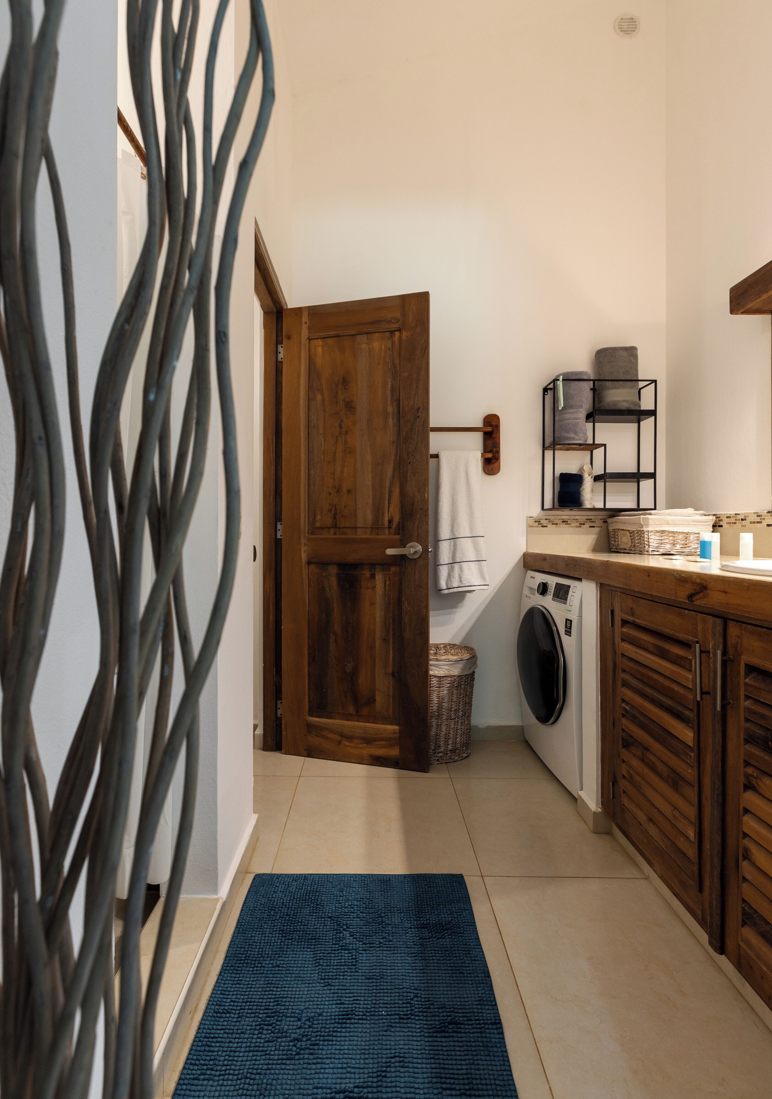 A laundry area with a washing machine, wooden cabinets, and a blue rug.