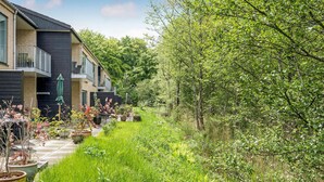 A residential building with a balcony and a garden area with various plants and a pathway. - Nice apartment in Hornbæk with WiFi (Hornbæk)