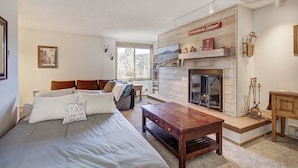 A cozy room with a bed, a wooden coffee table, a fireplace, and a bookshelf. - Prime Location Incredible Amenities Hot Tub Wifi (Breckenridge)