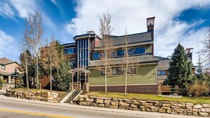A multi-story building with a stone staircase leading to a covered entrance, surrounded by trees and a clear sky. - Prime Location Incredible Amenities Hot Tub Wifi (Breckenridge)