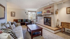 A cozy living room with a fireplace, a sofa, a coffee table, and a bookshelf. - Prime Location Incredible Amenities Hot Tub Wifi (Breckenridge)