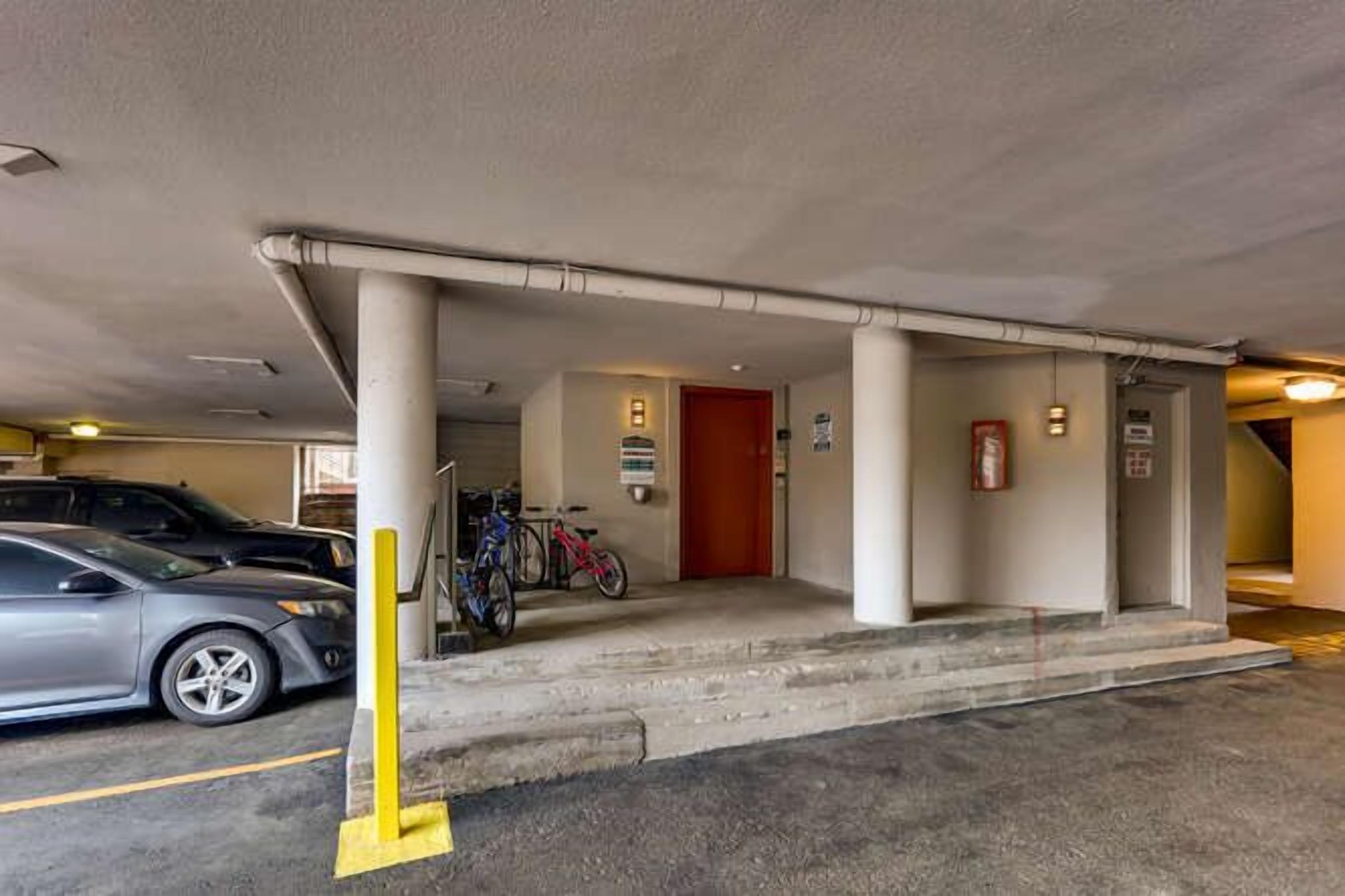 A parking garage entrance with a red door, a fire extinguisher, and a yellow safety line.