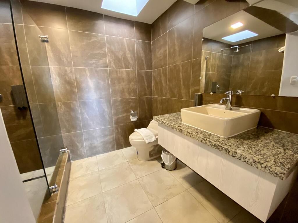Un bagno moderno con uno specchio grande, un lavandino e una zona doccia.