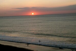 Un atardecer sobre un mar tranquilo con una playa al frente.