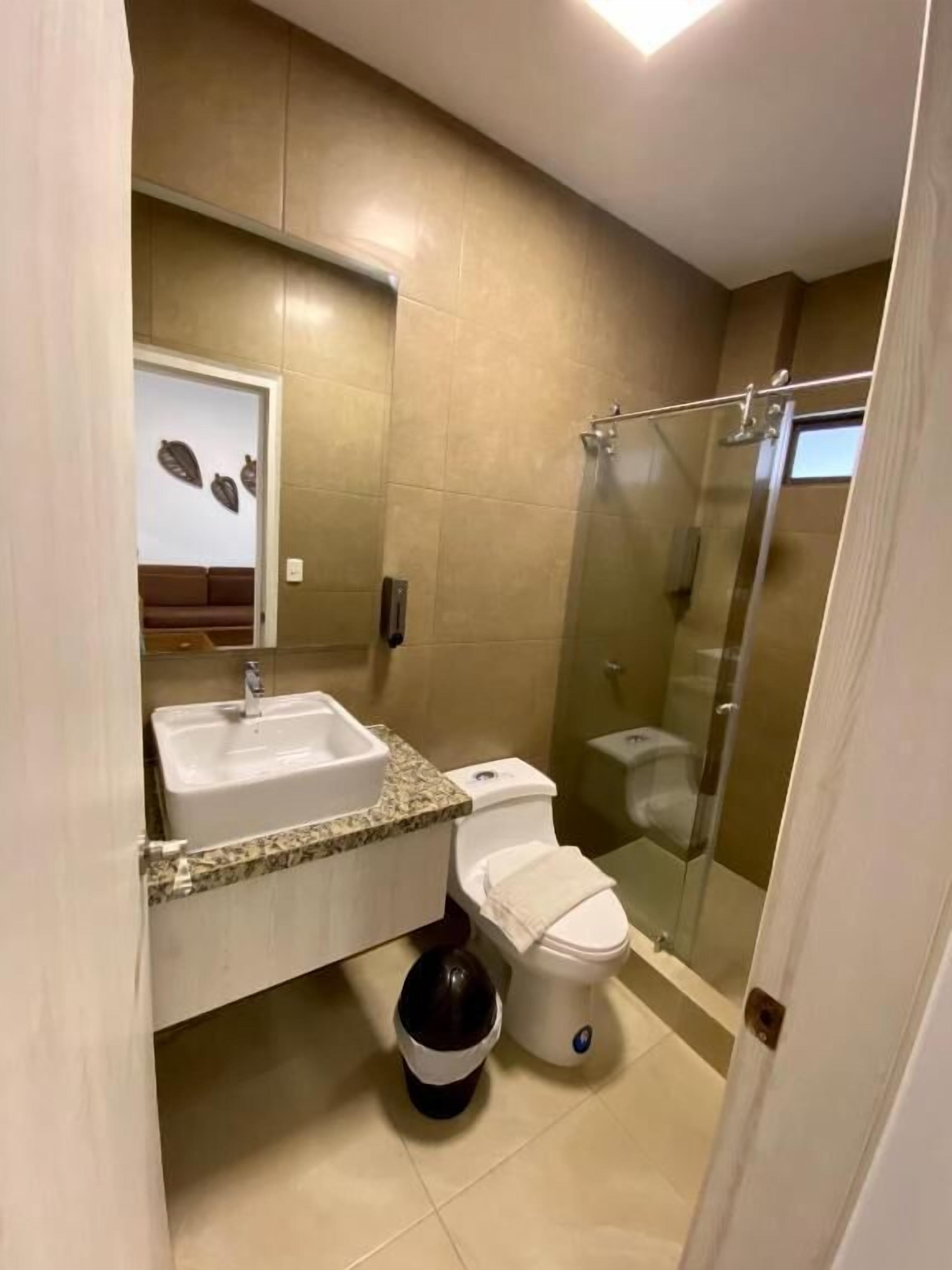 A bathroom with a sink, toilet, and glass shower enclosure.