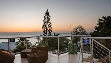 Ein Balkon mit Korbmöbeln, Blick auf das Meer und ein Schild mit Rauchverbot.