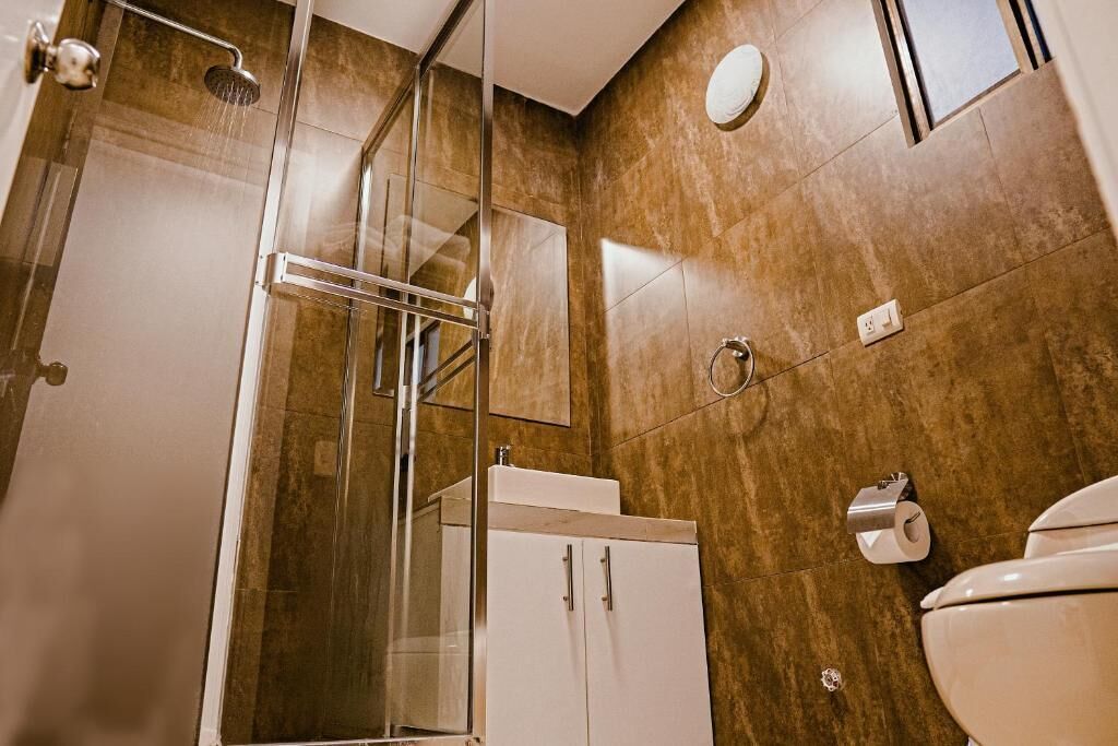 A modern bathroom with a glass shower enclosure, a white sink, and a toilet.