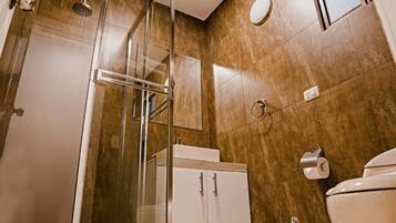 A modern bathroom with a glass shower enclosure, a white sink, and a toilet.