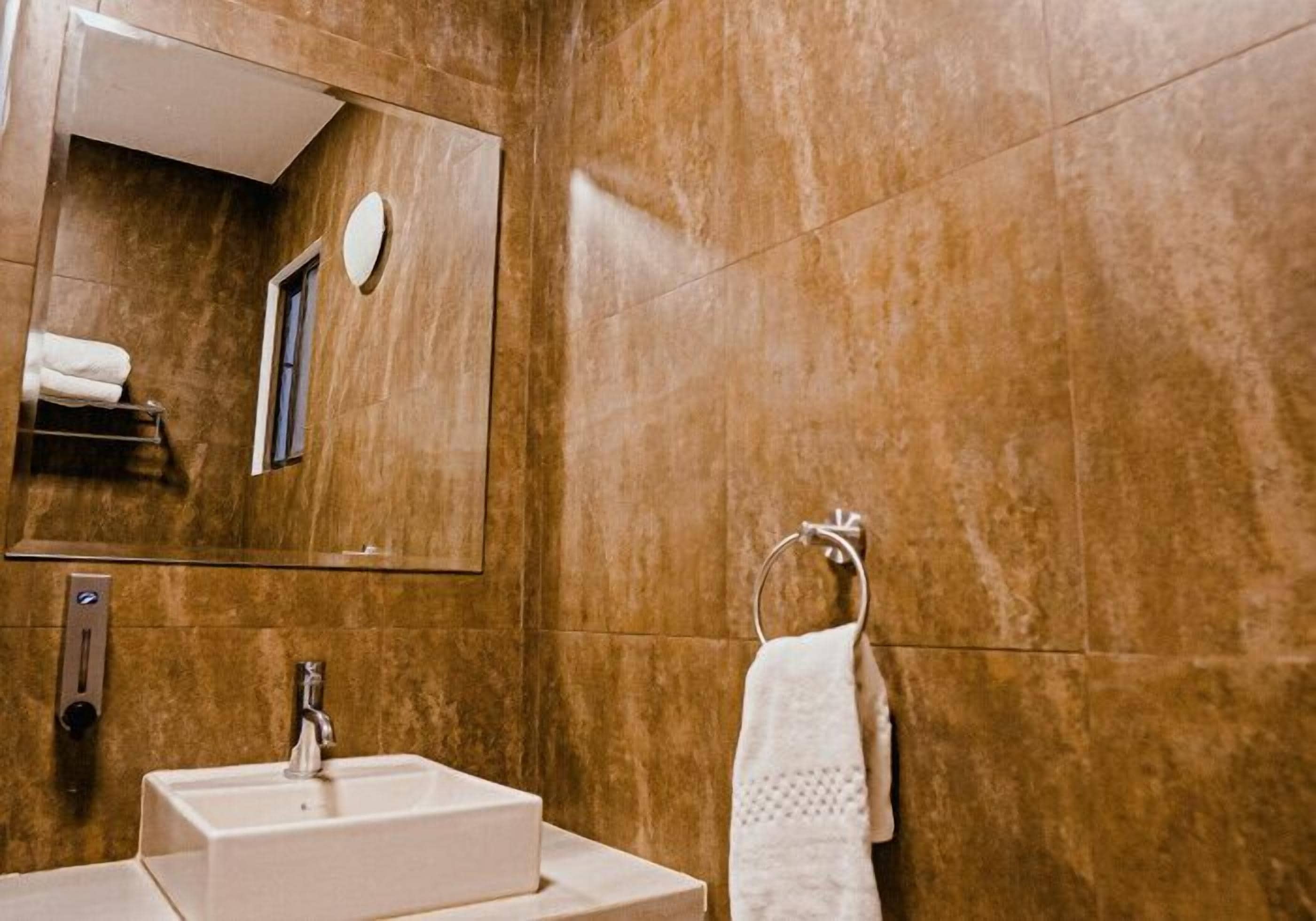 A bathroom with a sink, mirror, and towel rack.