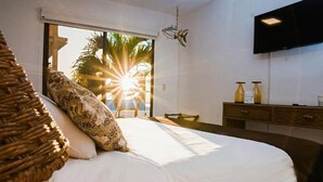 Un dormitorio con cama, televisor, escritorio y vista al mar.