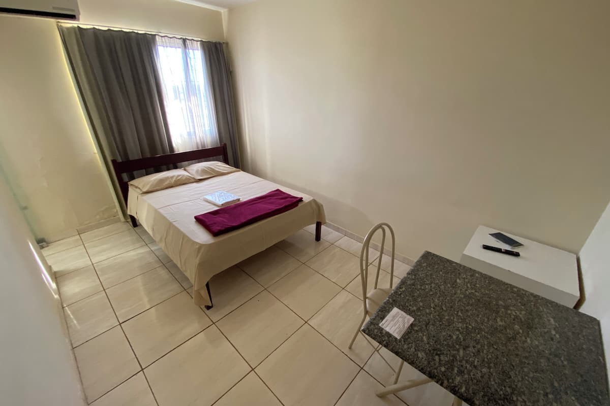 A hotel room with a bed, a desk, and a chair.