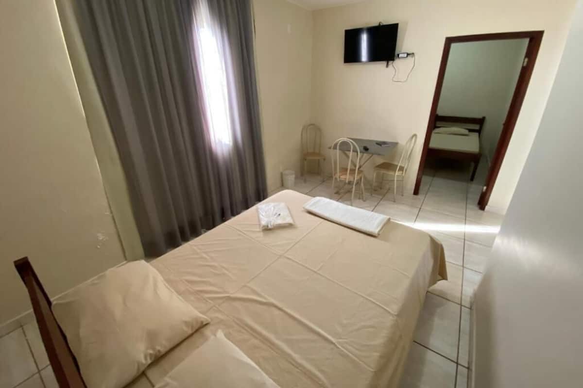 A hotel room with a bed, a desk, and a television.