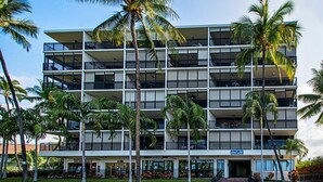 Monikerroksinen hotelli, jossa on parvekkeita, palmuja ja kyltti, jossa lukee ”Hawaiian Gardens”.