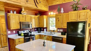 A kitchen with wooden cabinets, a central island, a black refrigerator, and a microwave. - Lutsen Log Lodge! Ski, Hike, Golf & Bike (Lutsen)
